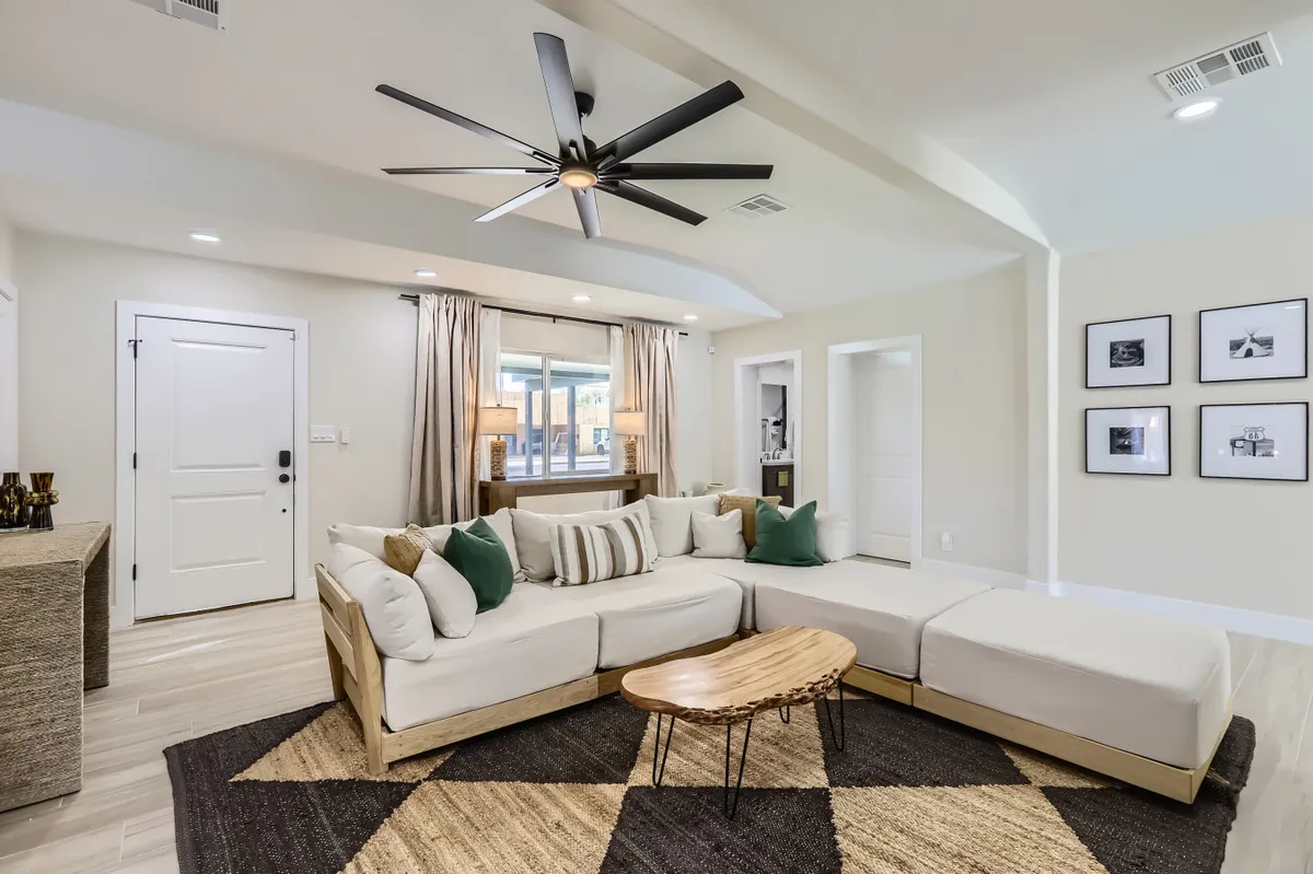 A comfortable living room with a cozy sofa, stylish coffee table, and a large window with curtains that lets in plenty of daylight. The walls feature tasteful art, contributing to a relaxing and inviting atmosphere—the perfect spot to unwind after a day out.
