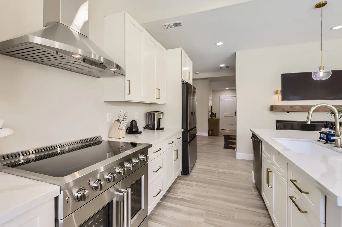 A bright, modern kitchen featuring stainless steel appliances, white cabinetry, and marble countertops. The space is welcoming and functional, ideal for preparing meals with family or entertaining guests. The open layout encourages gathering and sharing experiences.