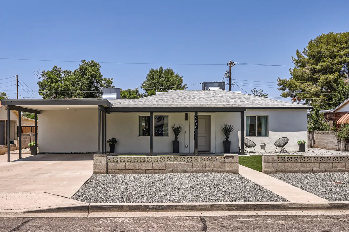 This image shows a welcoming front porch with comfortable seating, a landscaped gravel yard, and a decorative wall. The space is shaded and inviting, ideal for relaxing outdoors and soaking up the neighborhood’s tranquil vibe. Subtle greenery and thoughtful landscaping add to the outdoor charm.