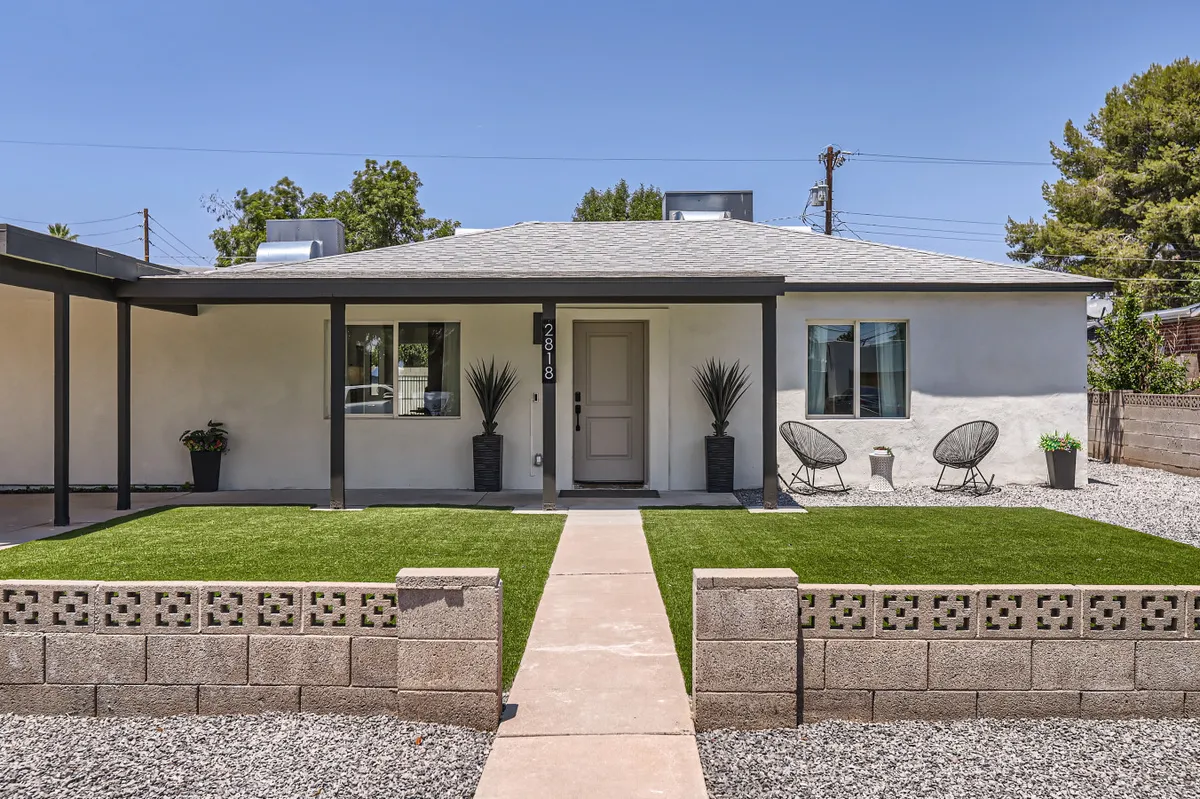 This exterior image shows the front door of the home, surrounded by a landscaped lawn and inviting outdoor seating. The scene exudes a sense of welcome and tranquility, suggesting both privacy and a connection to the neighborhood. The outdoor seating area hints at opportunities for relaxation during breaks from work, while the maintained lawn and porch evoke a residential, resort-like atmosphere.